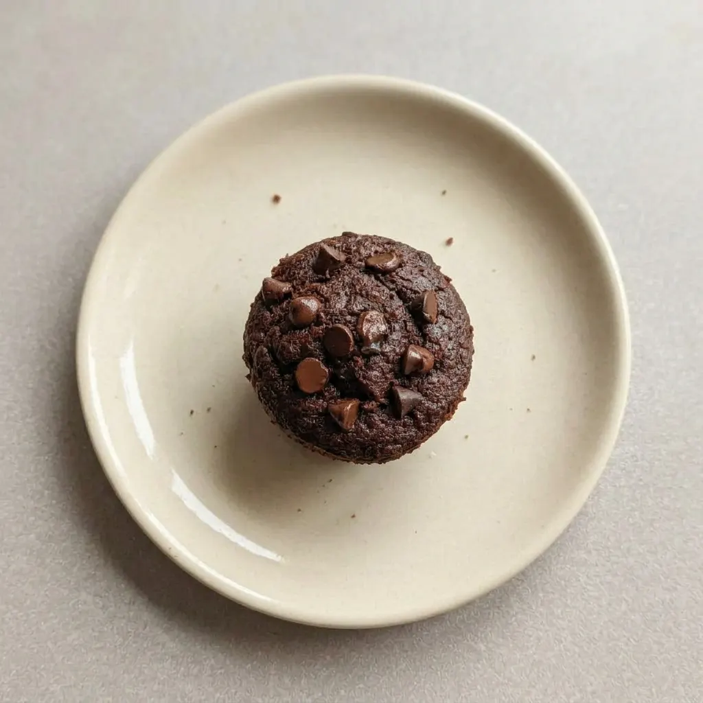 Plated chocolate muffin with a cracked top and melted chocolate chips.
