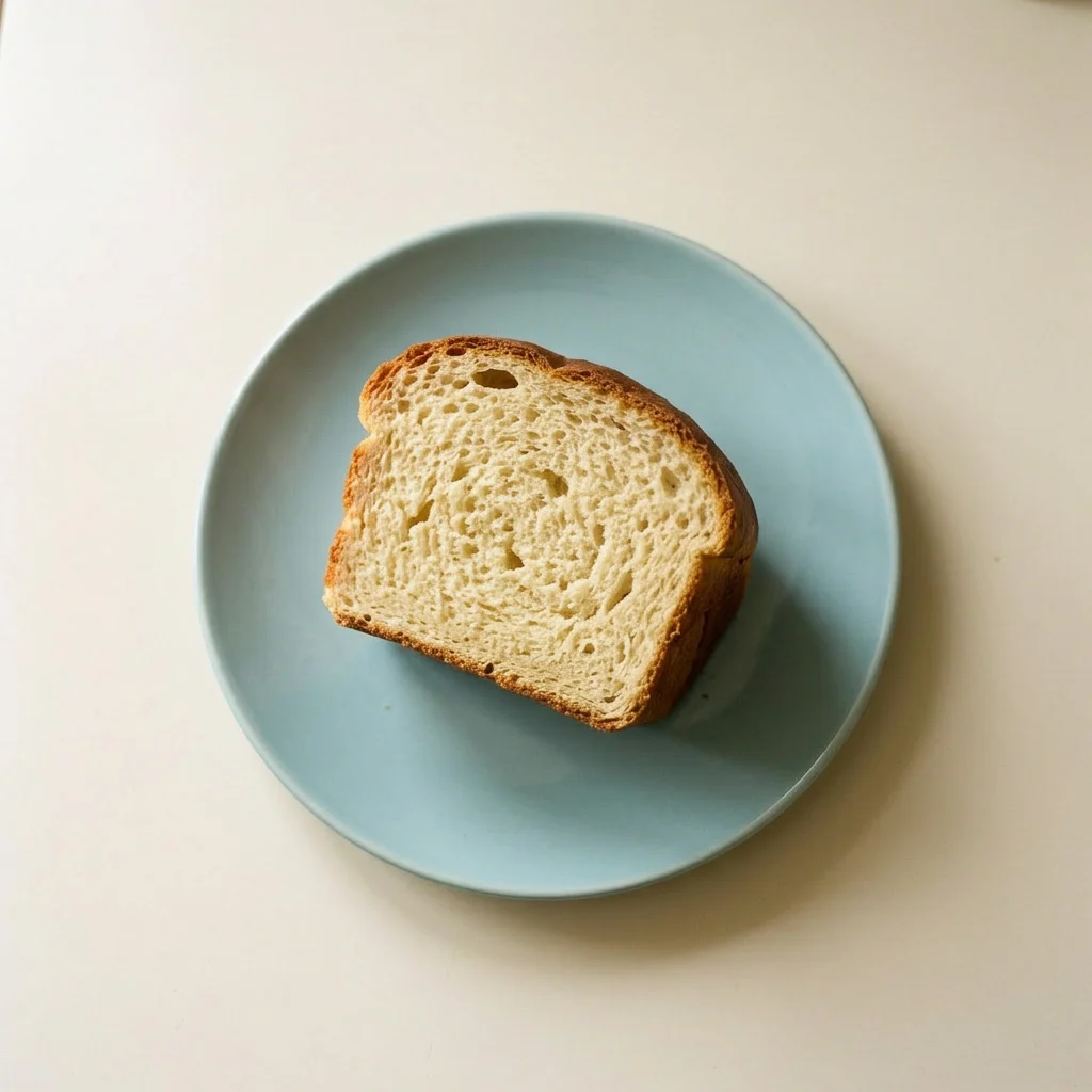 Plated slice of bread on a small dish, topped with a pat of butter melting into the warm crumb.