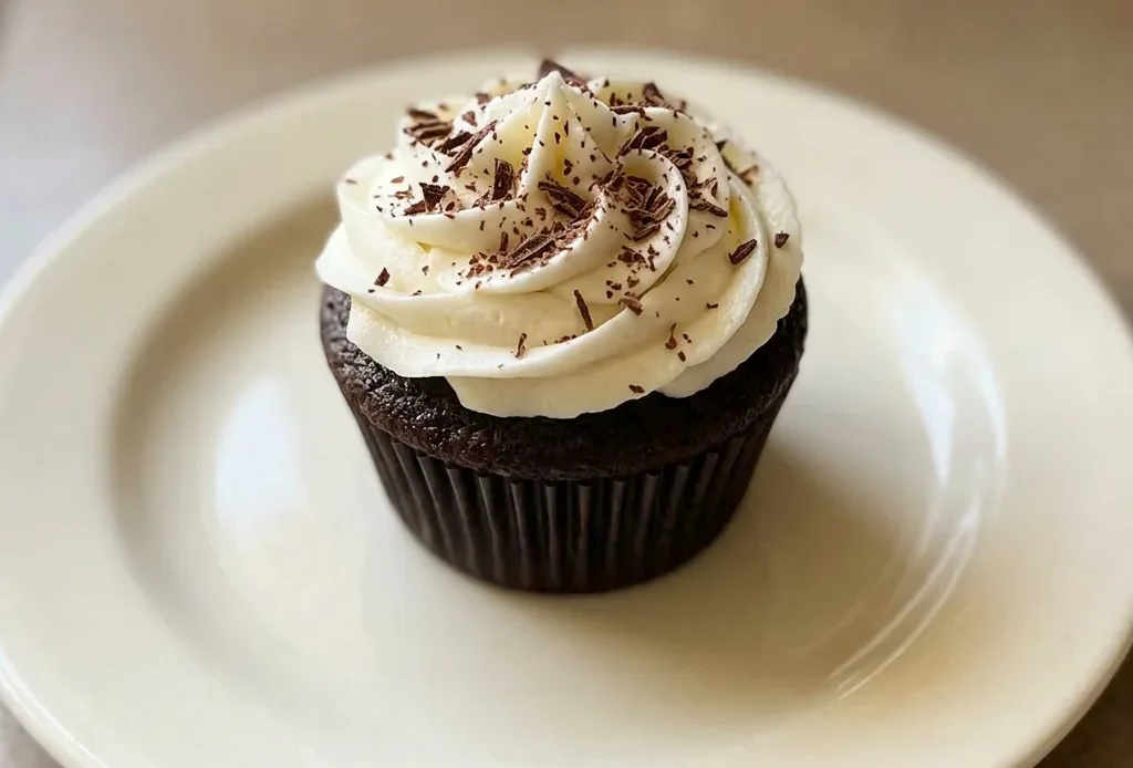 Bird's-eye view of two chocolate cupcakes with vanilla buttercream swirls and cocoa powder dusting.