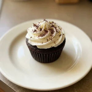 Bird's-eye view of two chocolate cupcakes with vanilla buttercream swirls and cocoa powder dusting.
