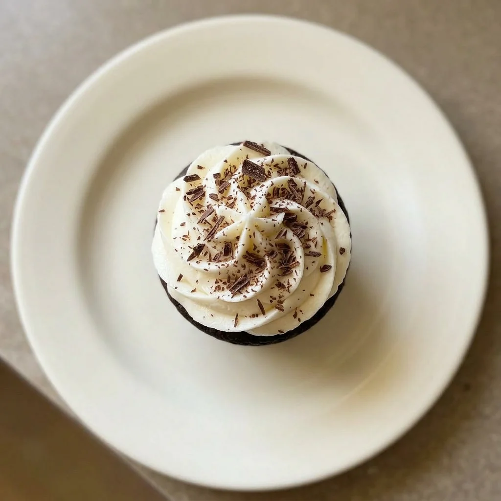 Ready to serve: chocolate cupcake topped with vanilla buttercream, chocolate shavings, and a coffee bean.