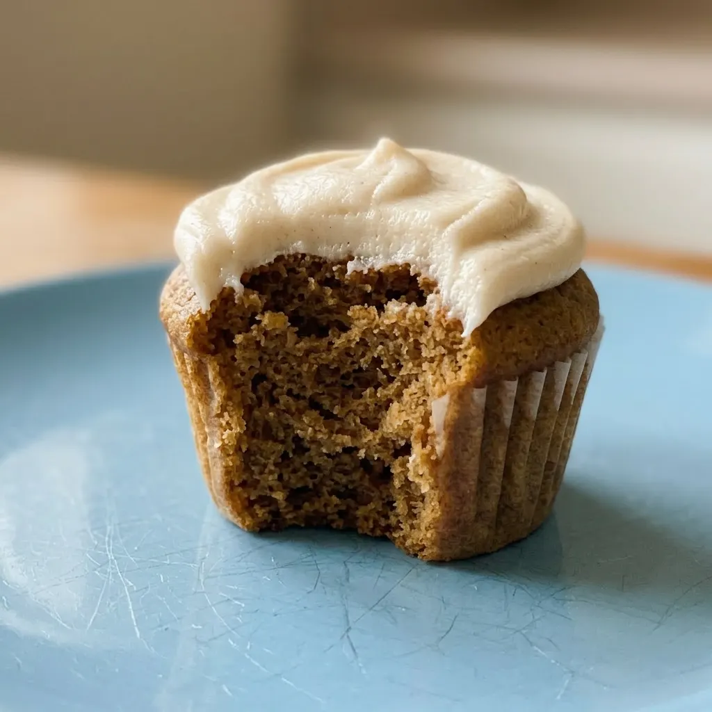 Zoomed in on a single cupcake with a swirl of white frosting and rainbow sprinkles, showing a moist crumb.