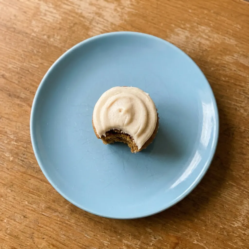 Ready to serve: two cupcakes with buttercream and sprinkles, one bitten, on a napkin.