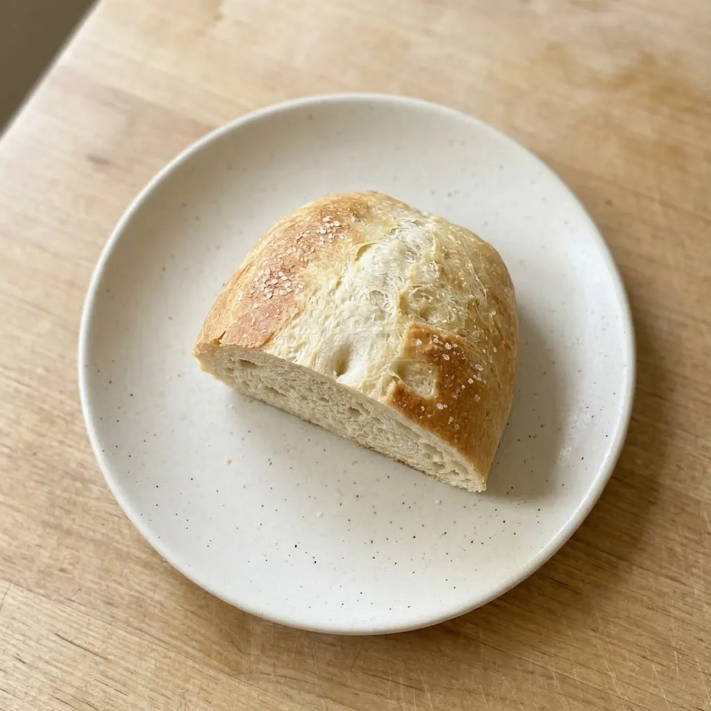Plated bread slices arranged with a small dish of olive oil for dipping, the crust glistening with honey and salt.