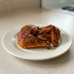 Bird's-eye view of a whole roasted chicken with crispy golden skin, seasoned with visible specks of herbs and spices.