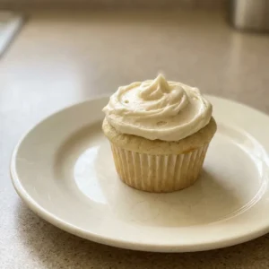 Overhead shot of a white-frosted vanilla cupcake cake with visible butter and vanilla specks.