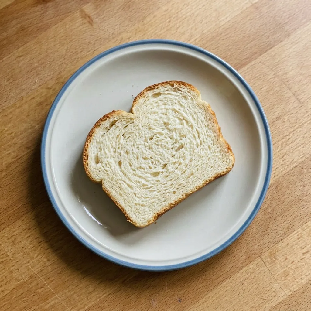 A serving of sliced bread with a pat of butter on top, crust browned and crumb visible.