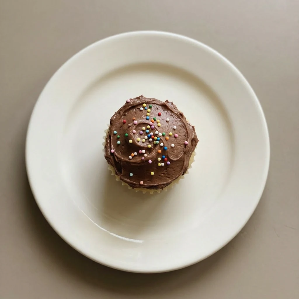 A plate of yellow cupcakes with chocolate buttercream frosting and sprinkles.