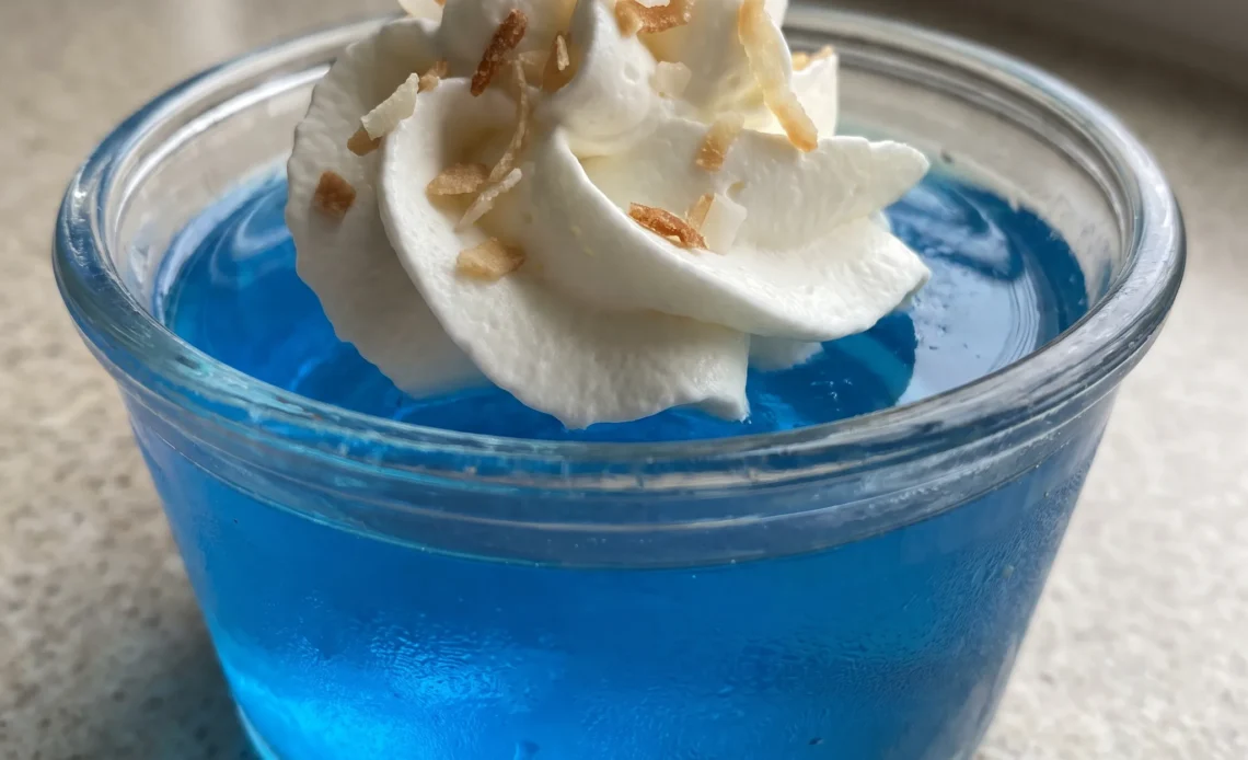 Blue gelatin shots topped with whipped cream and toasted coconut flakes.