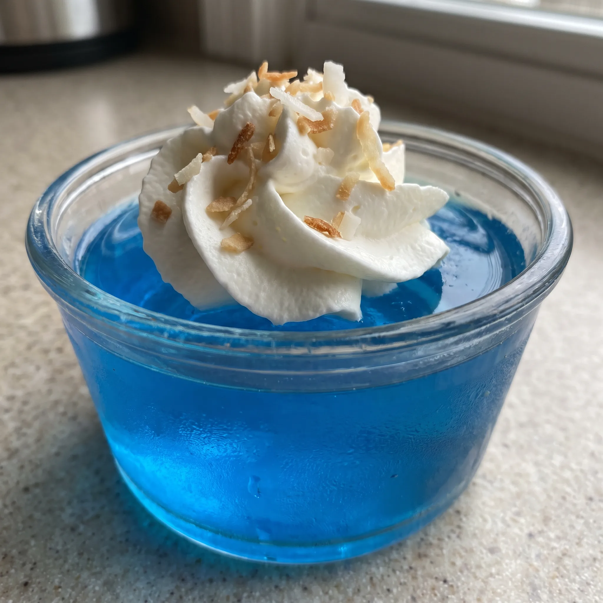 Blue gelatin shots topped with whipped cream and toasted coconut flakes.
