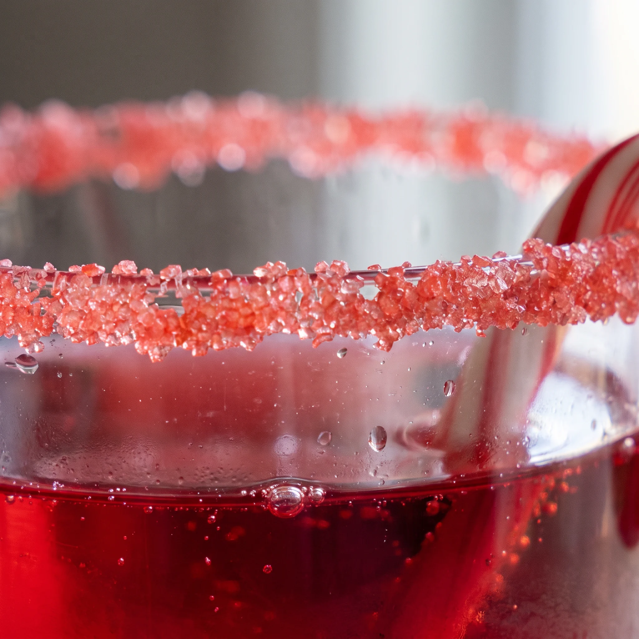 Candy Cane Mocktail with a frothy red top, garnished with a striped candy cane, and visible bubbles rising through the liquid.