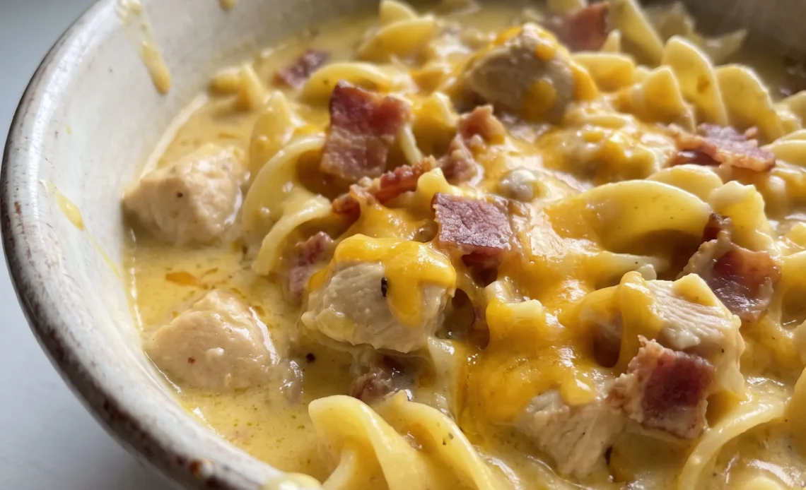 Crack chicken noodle soup with shredded chicken, egg noodles, creamy broth, and bacon bits.