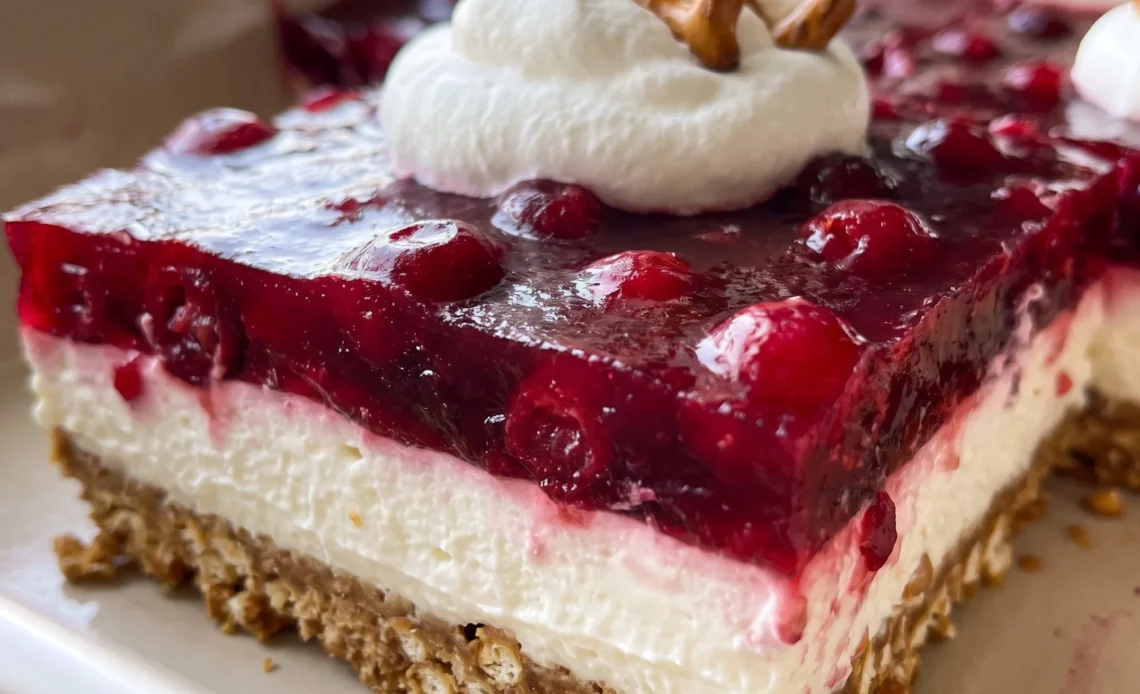 Cranberry pretzel salad with a pretzel crust, a cream cheese and Cool Whip layer, and a top of raspberry jello with cranberry sauce.