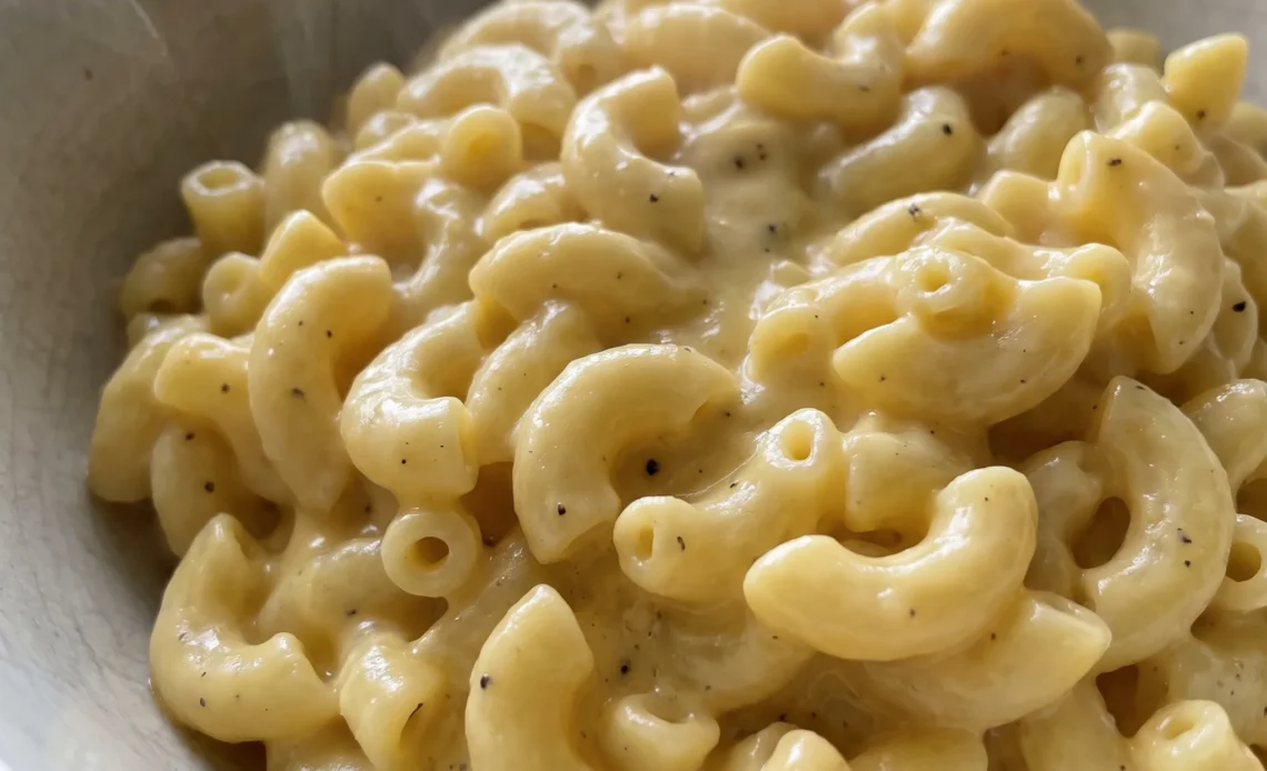 Creamy stovetop mac and cheese with elbow macaroni coated in a smooth, pale yellow sauce, topped with melted cheddar and gruyere.