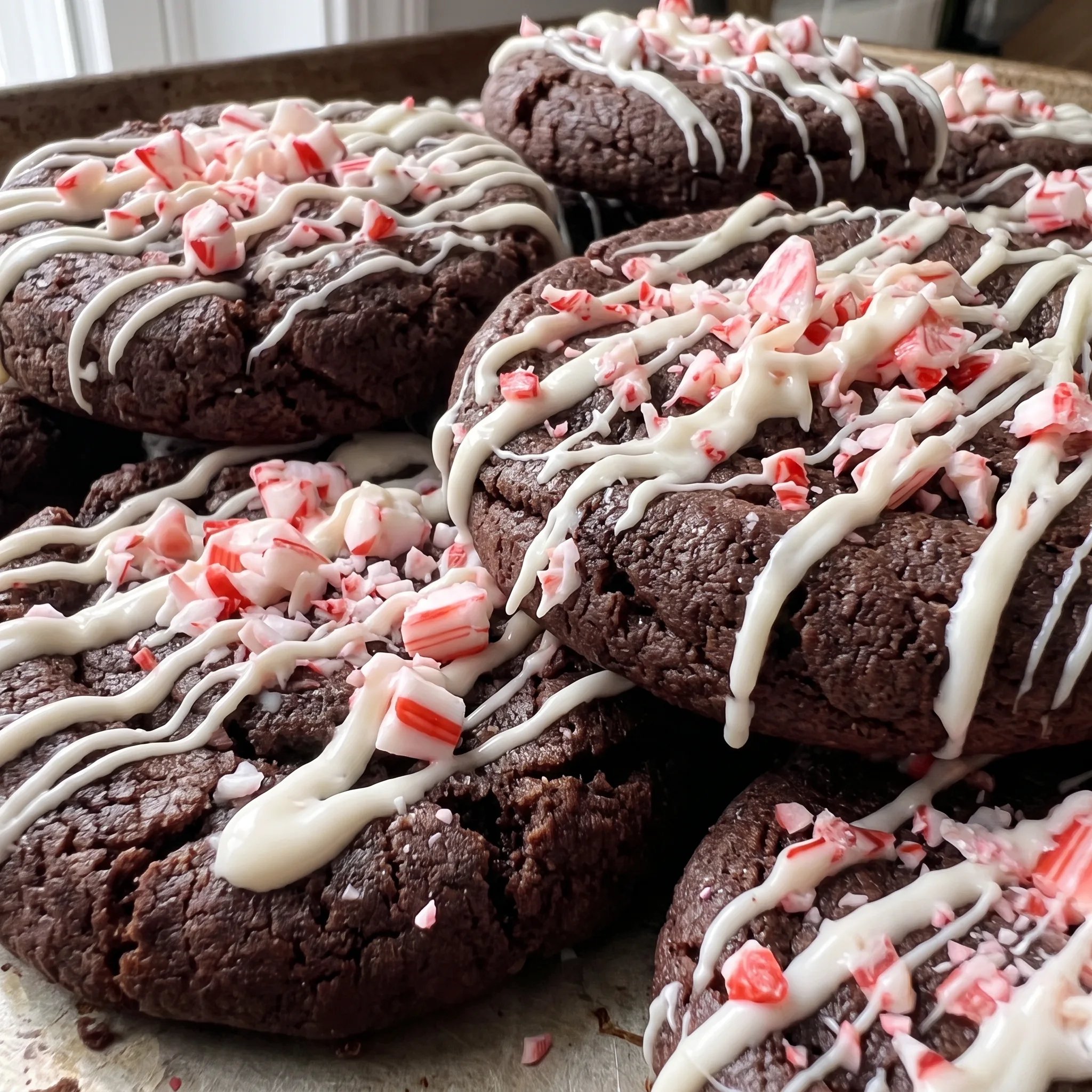 Cracked chocolate cookie surface with peppermint pieces and melted white chocolate swirls.