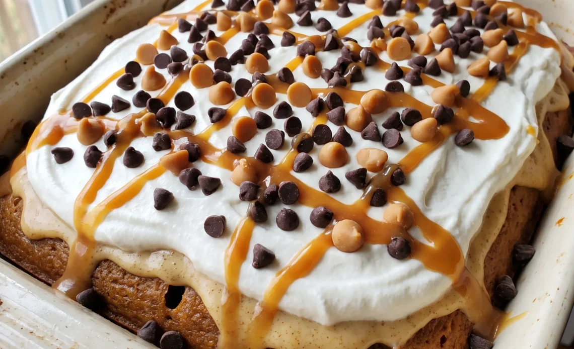Pumpkin spice poke cake with cream cheese frosting, Cool Whip, chocolate chips, caramel chips, and caramel topping.
