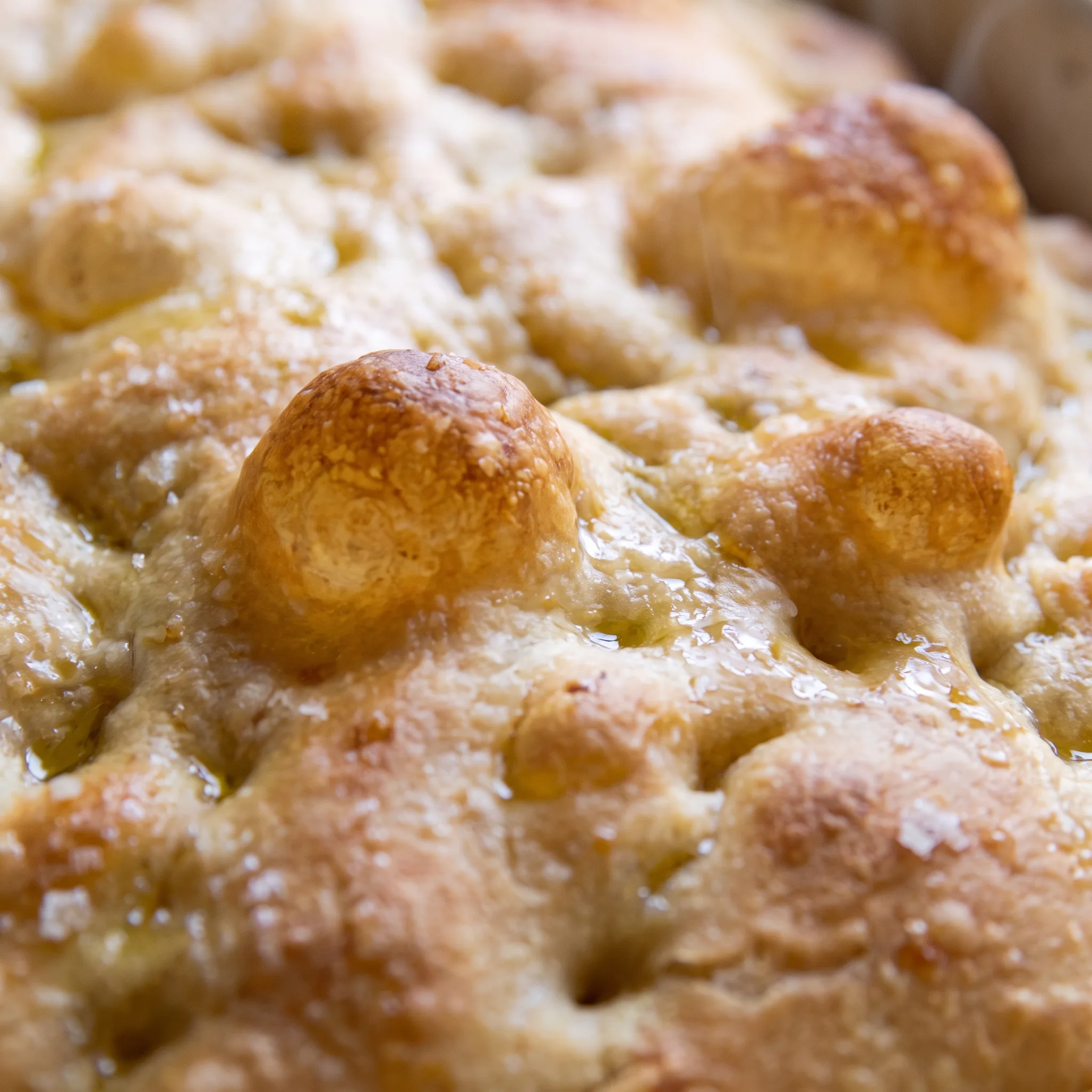 Dimpled golden bread with pools of olive oil in the indentations and flakes of sea salt on the crust.
