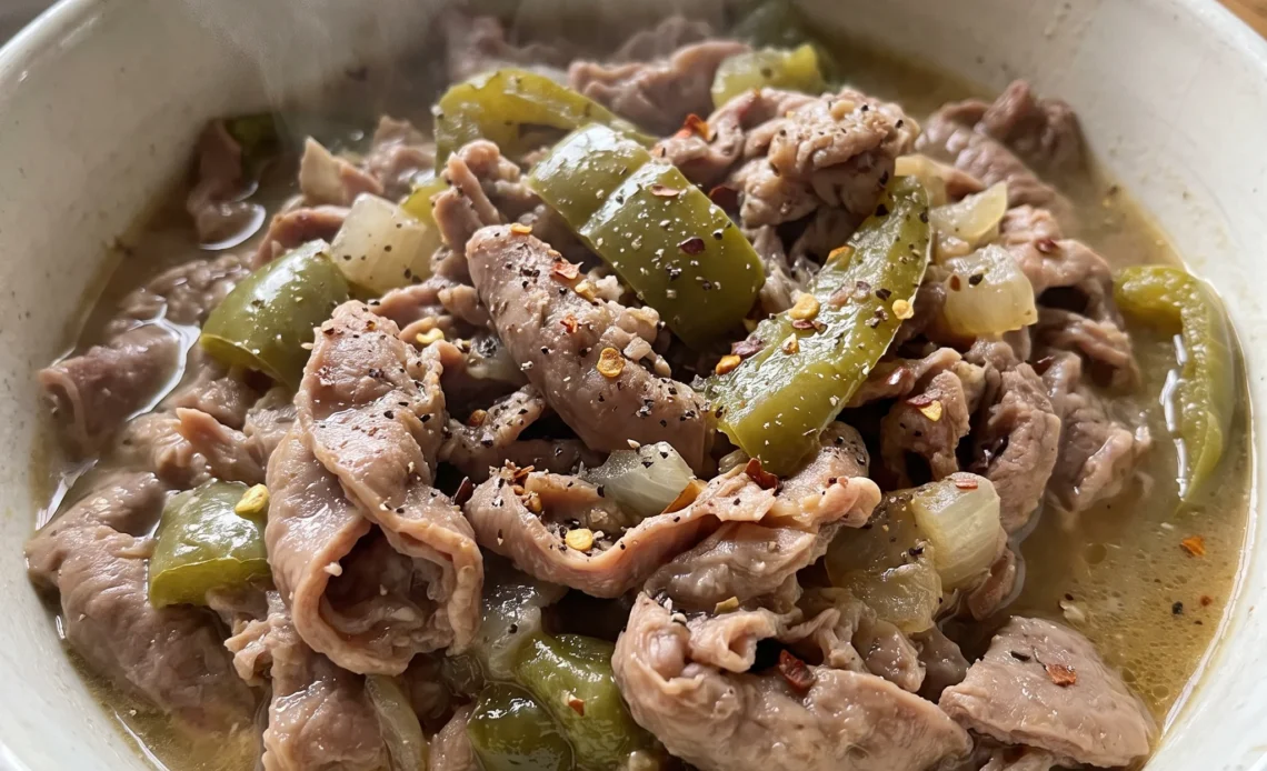 Southern chitterlings with onion, bell pepper, and garlic in a savory sauce, sprinkled with red pepper flakes.