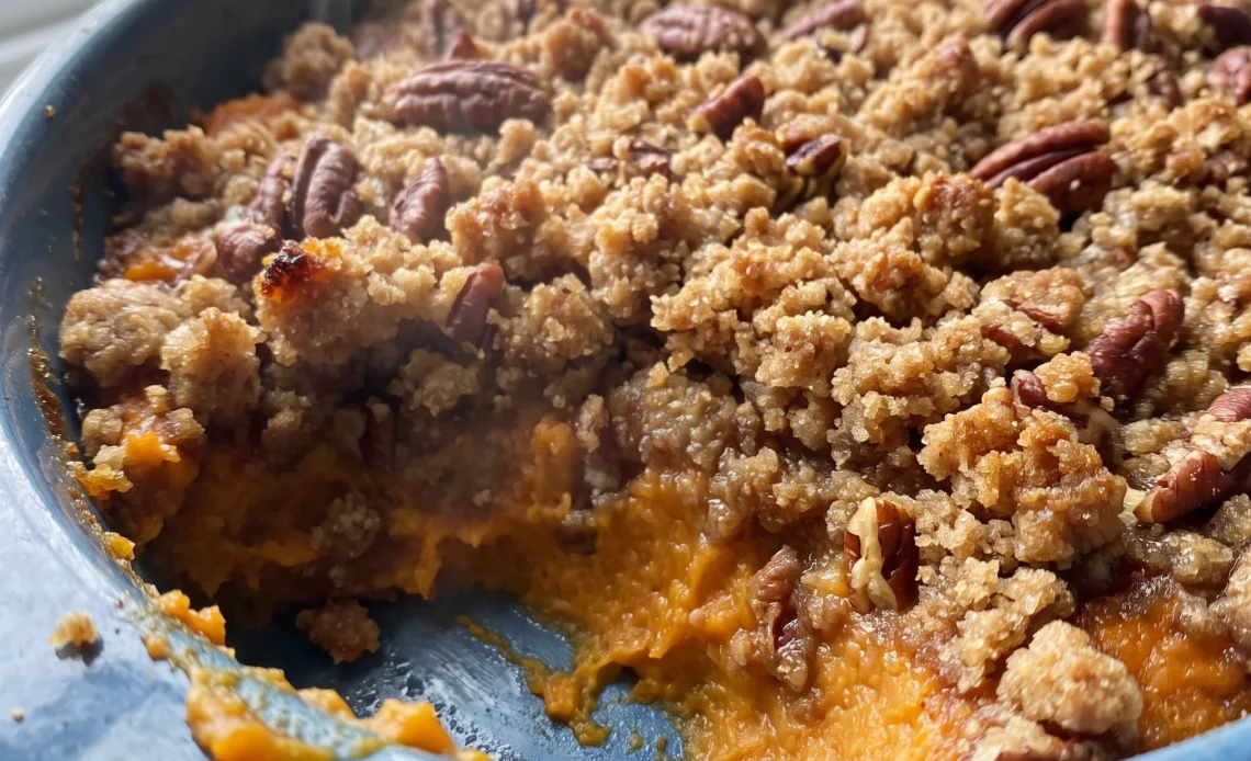 Sweet potato casserole with pecan topping, mashed sweet potatoes beneath a layer of brown sugar and butter glazed pecans.