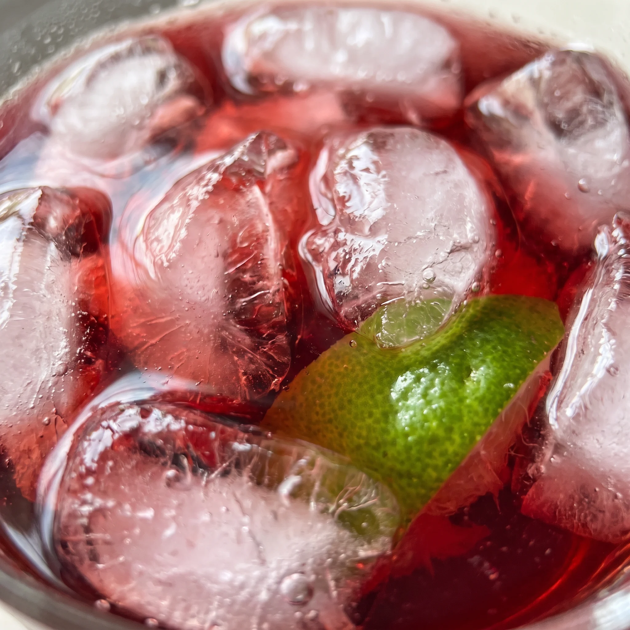 Cranberry juice and vodka mix, with a lime wedge adding a green contrast to the deep red drink.