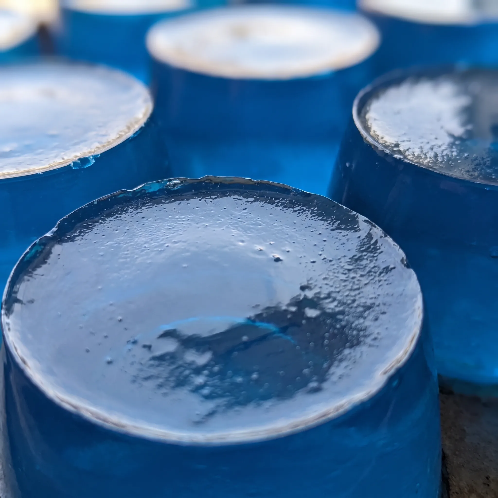 Glossy blue gelatin squares with a soft, jiggly texture, catching light on their smooth, wet surfaces.