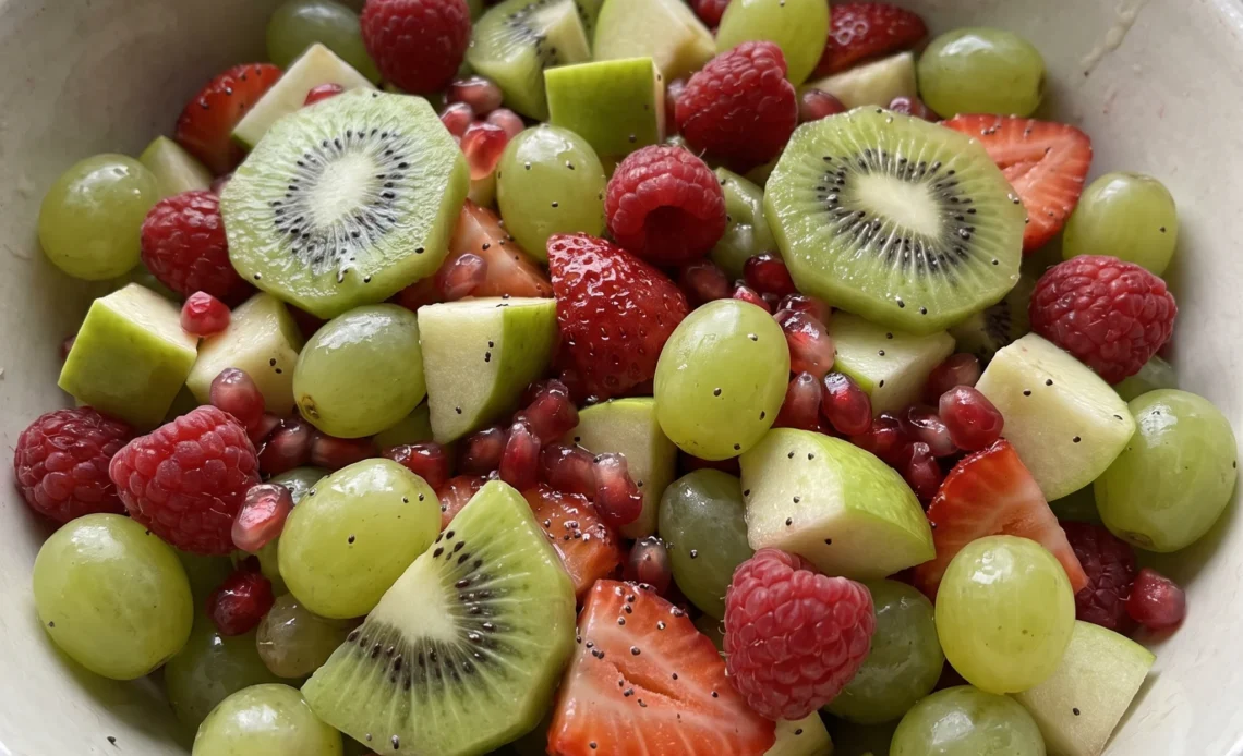 Christmas fruit salad with green grapes, kiwi slices, raspberries, strawberries and pomegranate arils in a mix of red and green.