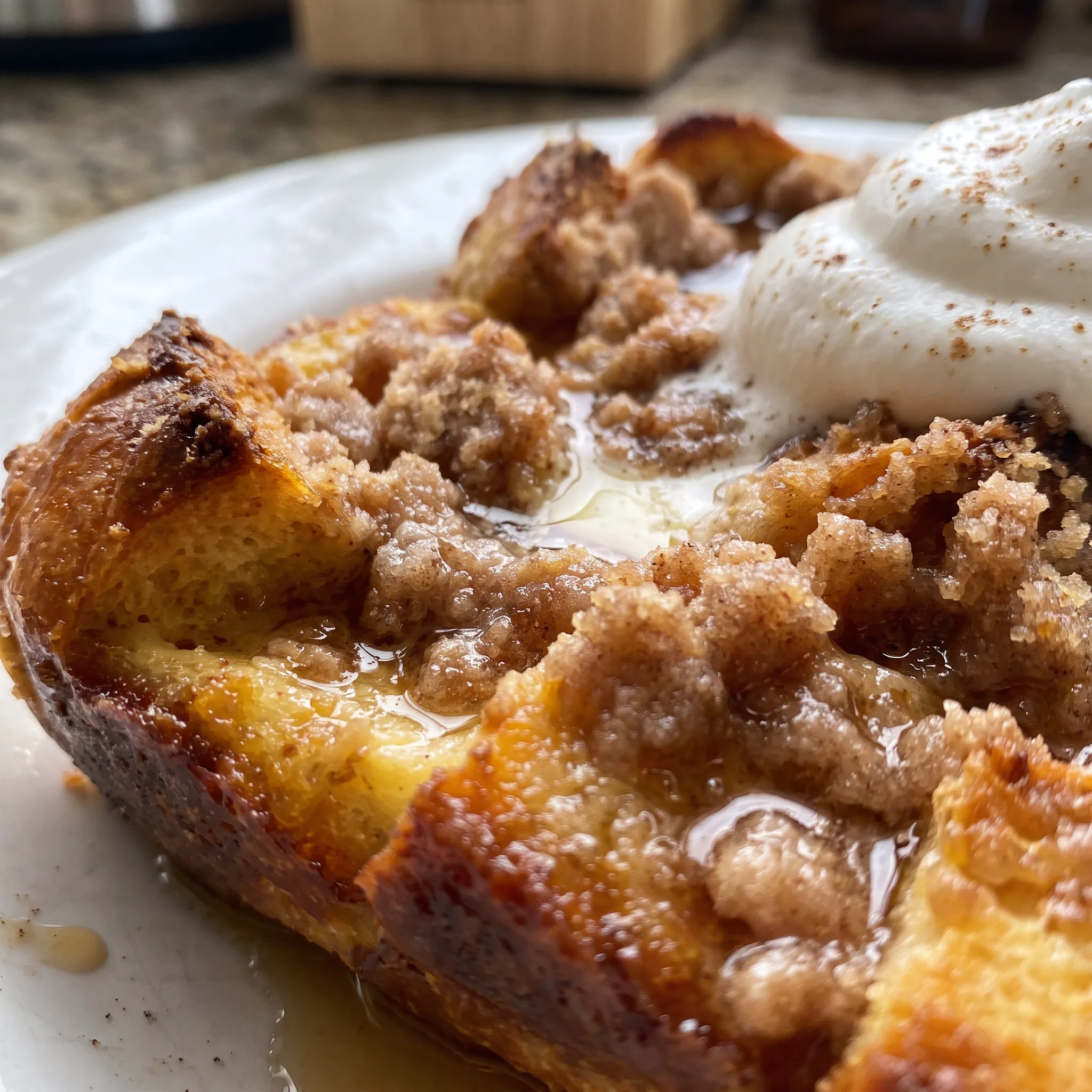Soft, custardy bread cubes with a crisp, buttery crumb topping in shades of gold and pale yellow.