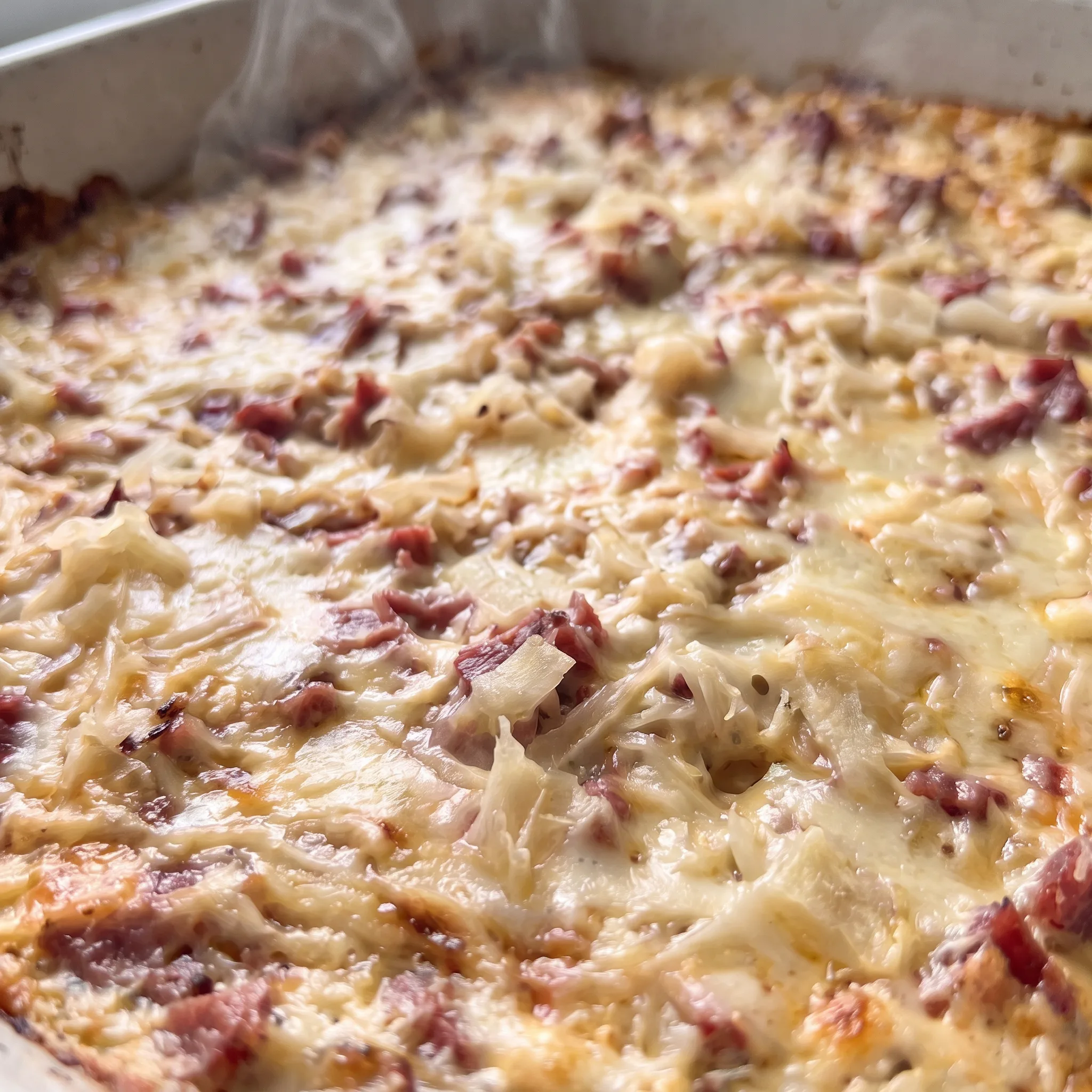 Golden melted Swiss cheese stretches over chunks of pink corned beef and tangy sauerkraut in a creamy dip.