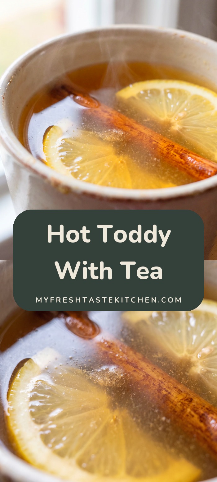 Mug of amber hot toddy with lemon slices and a cinnamon stick.