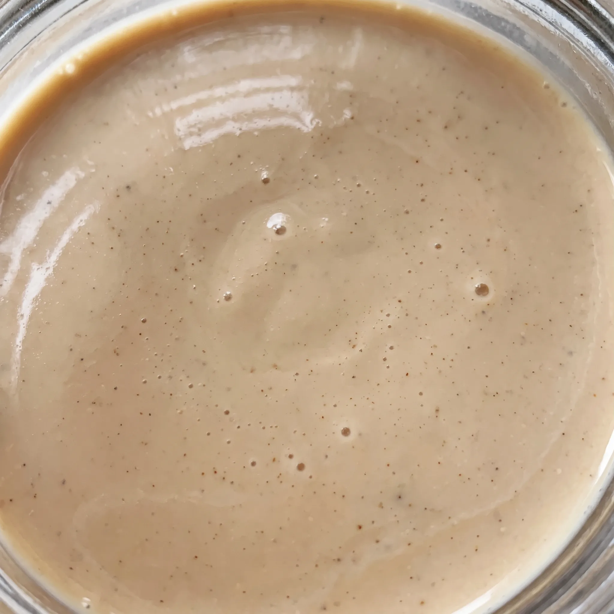 Creamy beige Irish cream liqueur, its silky surface catching light with a subtle coffee colored swirl.
