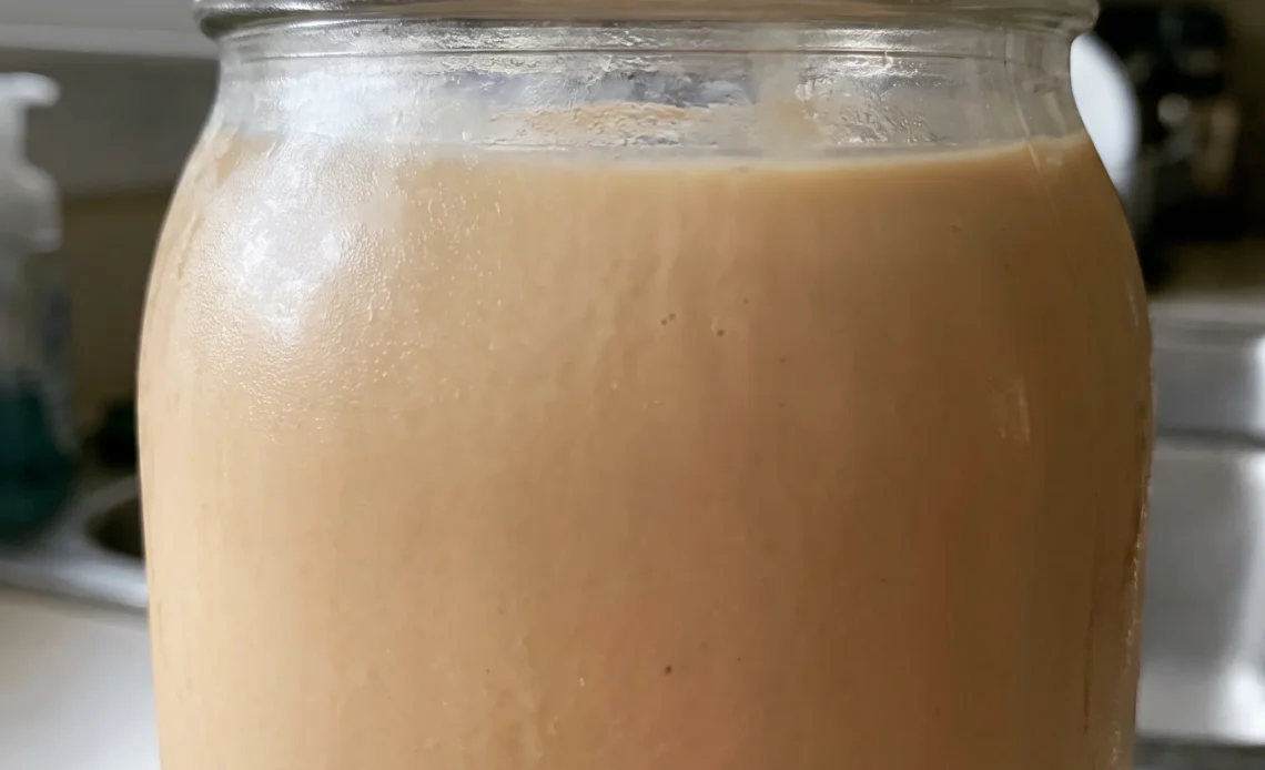 Irish cream liqueur in a glass, pale tan opaque liquid with a smooth surface and a faint coffee tint.