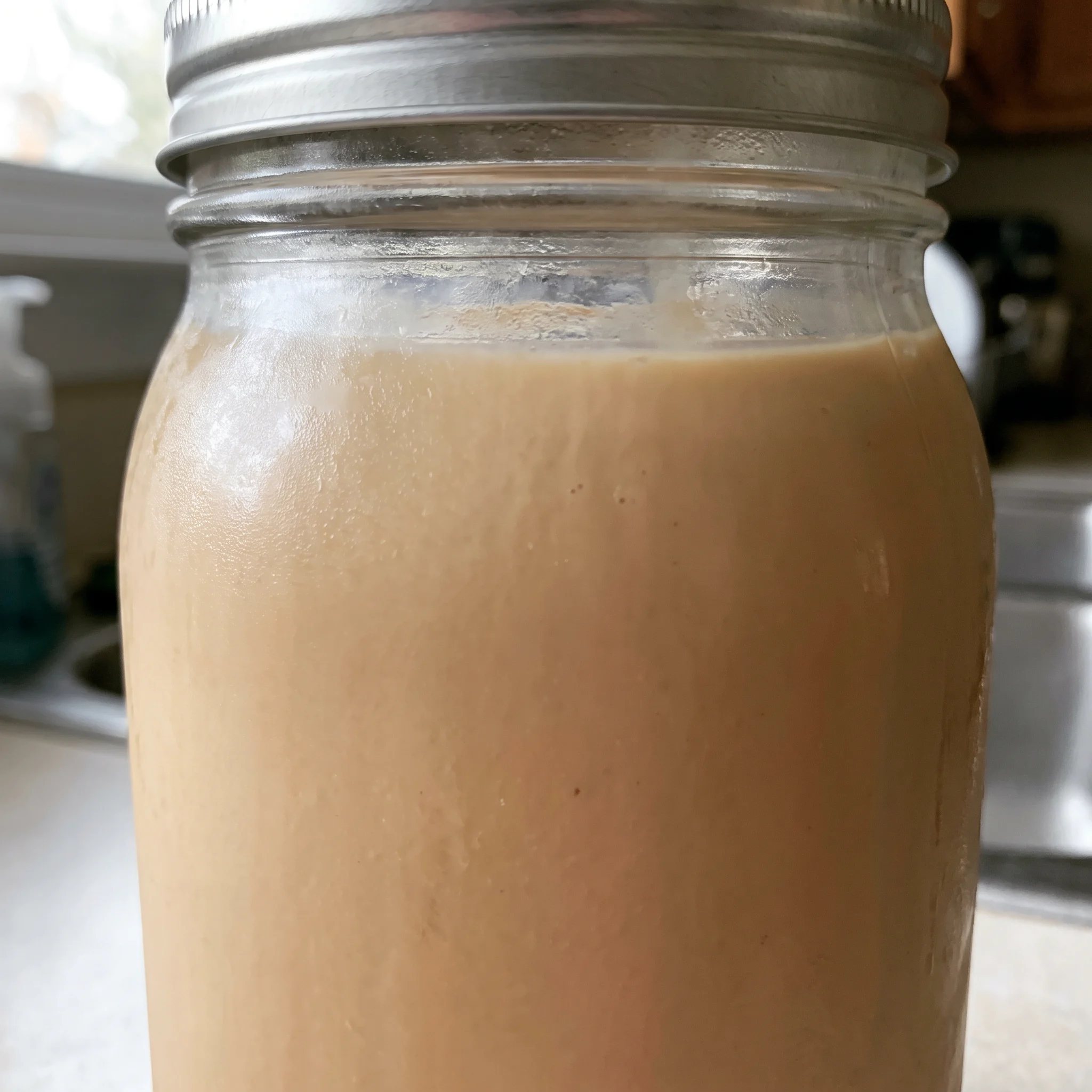Irish cream liqueur in a glass, pale tan opaque liquid with a smooth surface and a faint coffee tint.