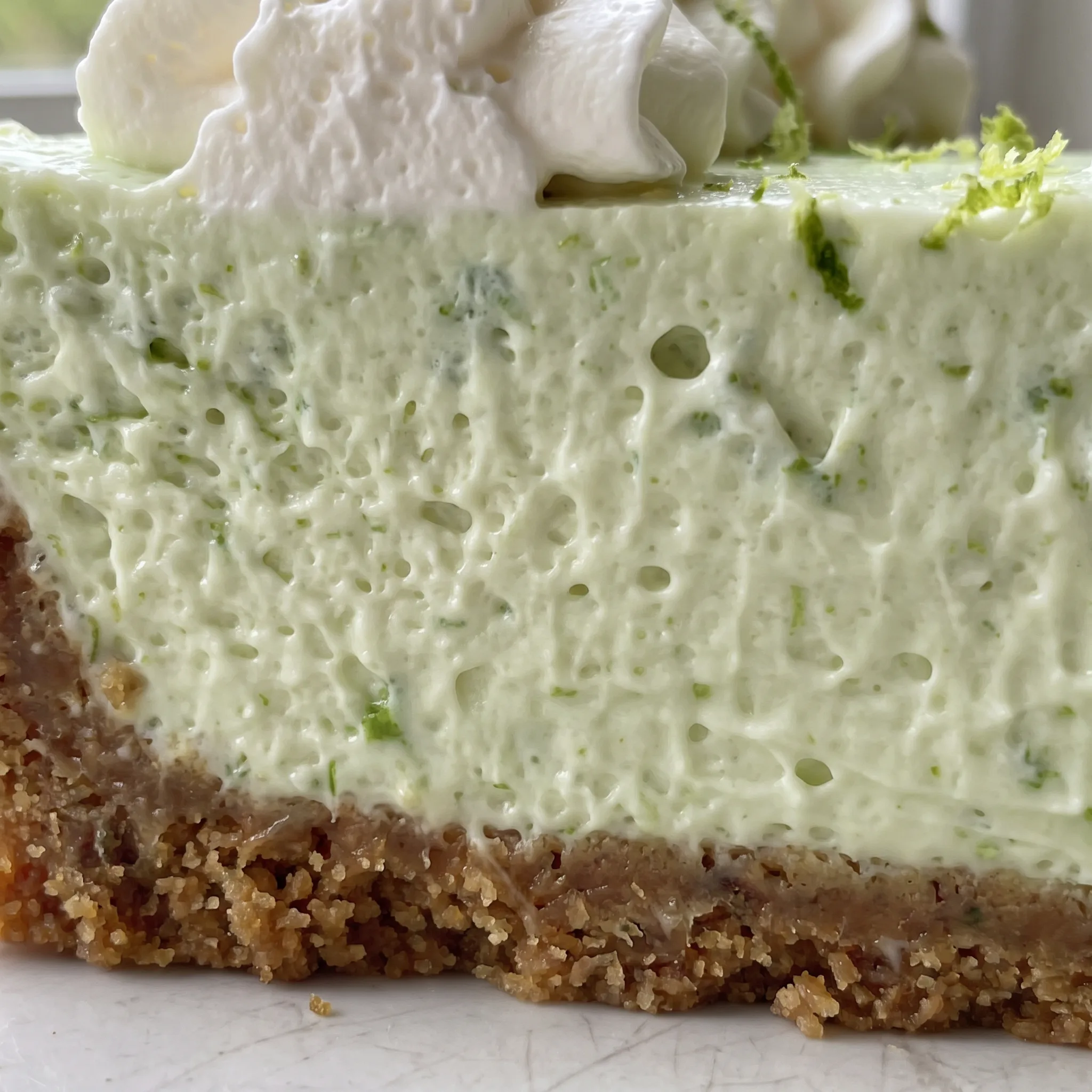 Smooth pale green key lime filling with a creamy texture, edged by a crumbly golden brown graham cracker crust.