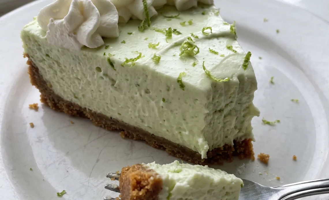 Key lime cheesecake with a graham cracker crust, topped with white whipped cream and thin green lime slices.