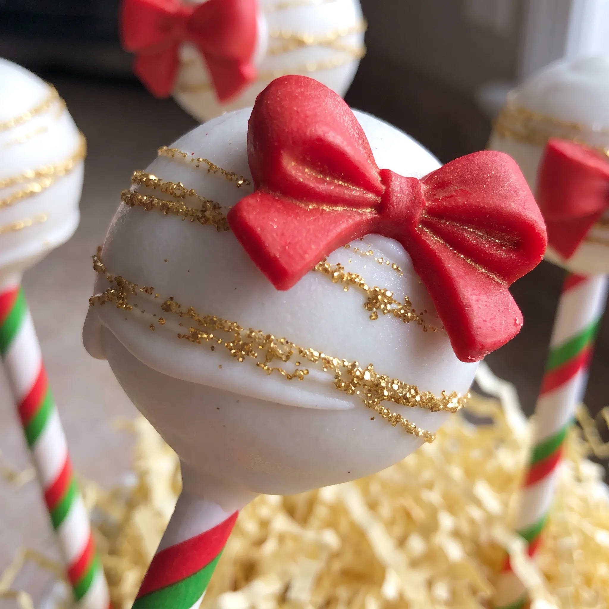 Smooth red, green, and white candy coating over vanilla cake, finished with tiny sugar sprinkles and small candy bows.